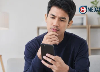 Ilustrasi seseorang menggunakan smartphone untuk mencari aplikasi penghasil uang.