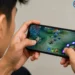 Ilustrasi pengguna memainkan game penghasil saldo DANA di smartphone untuk mengumpulkan poin reward.